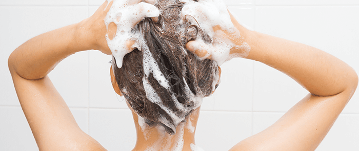 femme de dos en train de se laver les cheveux