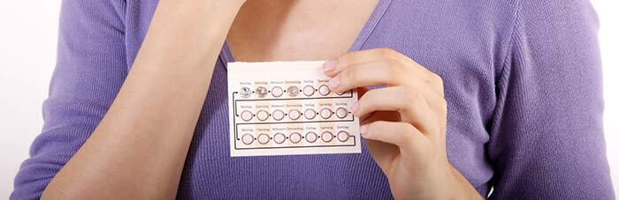 plaquette de pilule contraceptive tenue en main par un femme