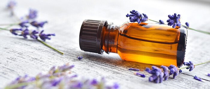 flacon d'huile essentielle de lavande entouré de fleurs de lavande