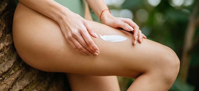 femme s'appliquant une crème raffermissante sur la cuisse
