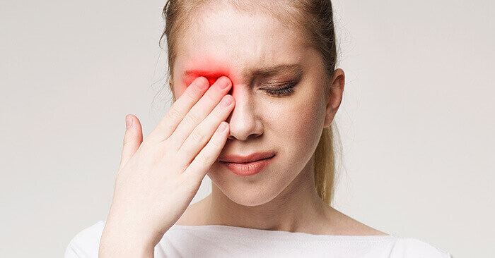 femme se tenant l'oeil suite à une infection oculaire