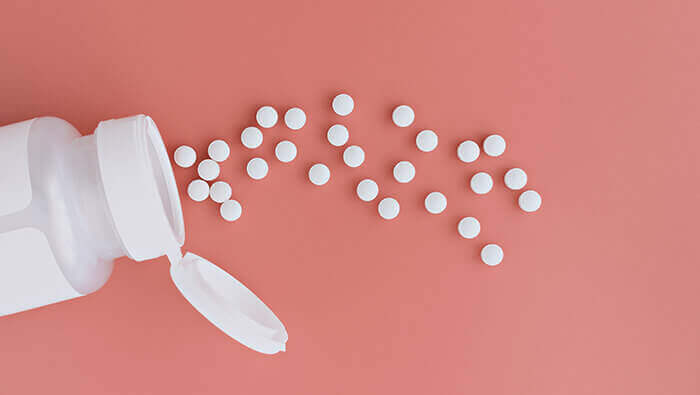 comprimés d'acide folique éparpillés sur un fond rose