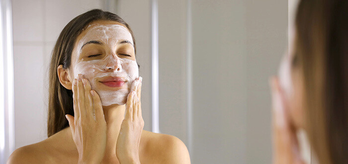 femme se nettoyant le visage avec une mousse nettoyante