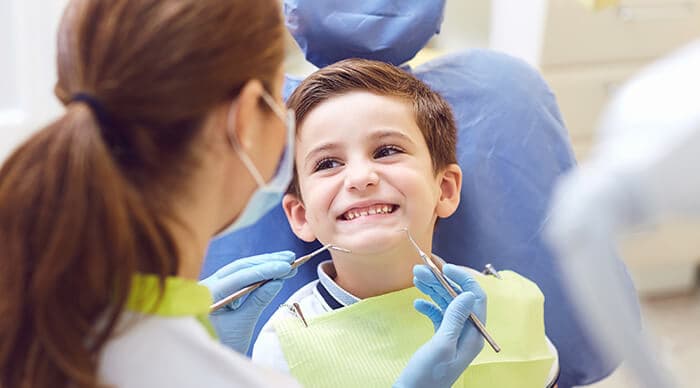 petit garçon souriant de toutes ses dents face à une dentiste