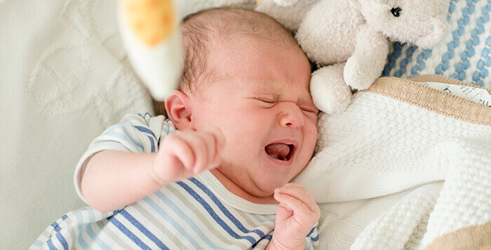 nourrisson pleurant dans son berceau sans doute gêné par une douleur