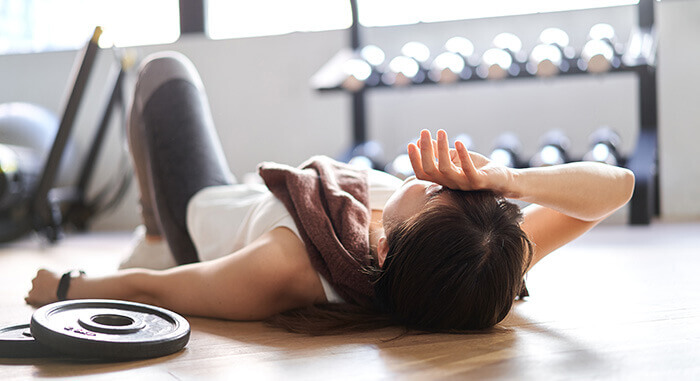 femme couchée au sol, éreintée après une séance de sport trop intense