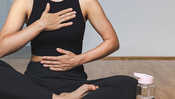 femme en tailleur en train de réaliser des exercices de respiration