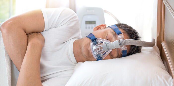 homme dormant avec un masque dans le cadre d'un traitement de l'apnée du sommeil