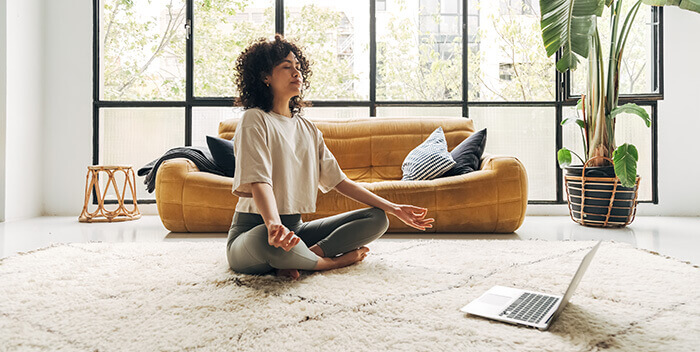femme pratiquant la méditation au milieu d'un salon