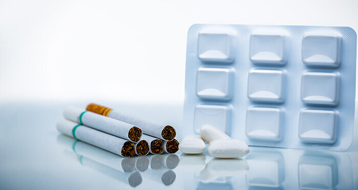 plaquette de gommes de nicotine à mâcher présenté à côté de 6 cigarettes