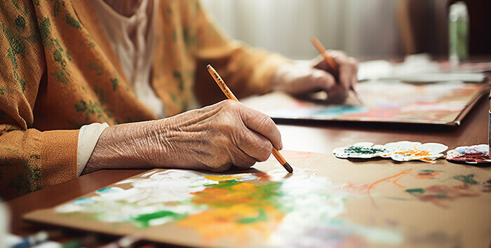 plan sur les mains d'une personne âgée dessinant dans le cadre d'une séance d'art-thérapie