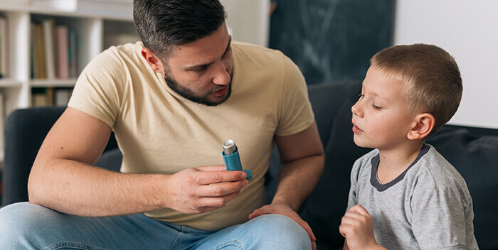 Papa expliquant à son petit garçon comment utiliser un bronchodilatateur en cas de crise d'asthme