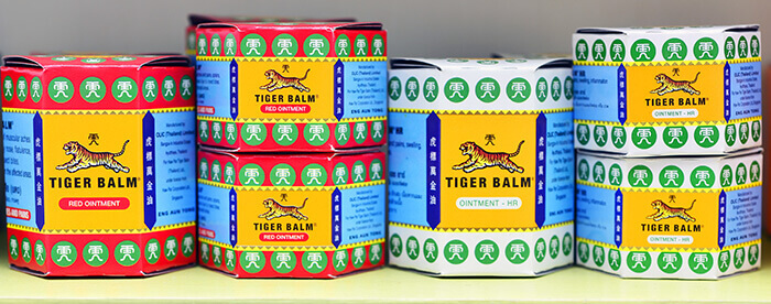 flacon de baume du tigre rouge et blanc posés sur une étagère