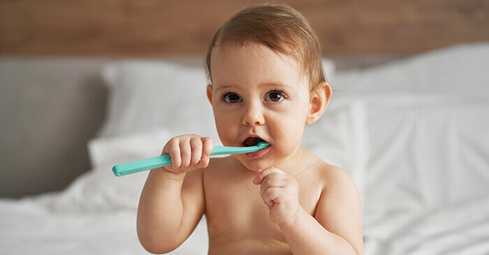 bébé en couche en train de se brosser les dents