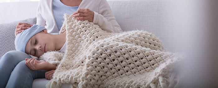 enfant atteinte d'un cancer dormant sur les genoux de sa mère