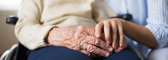 main d'une jeune femme tenant la main d'une personne âgée