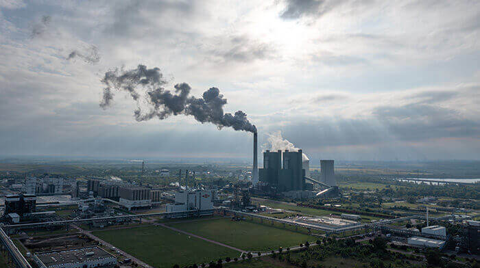 vue sur des cheminées d'usine crachant de la fumée noire