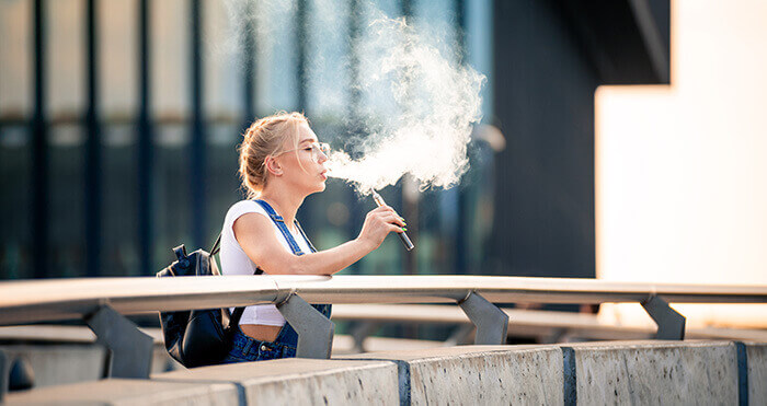 jeune femme fumant sur une cigarette électronique