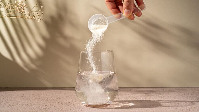 dose de collagène en poudre versée dans un verre d'eau