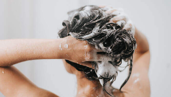 femme se faisant un shampooing antipelliculaire