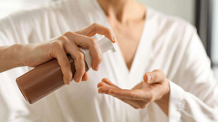 femme s'appretant à appliquer un autobronzant en versant du produit dans la paume de sa main