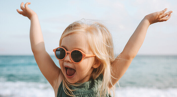 fillette blonde portant des lunettes de soleil orange à la plage