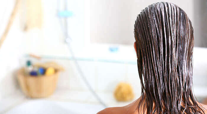 soin nourrissant posé sur des cheveux de femme dans une salle de bain