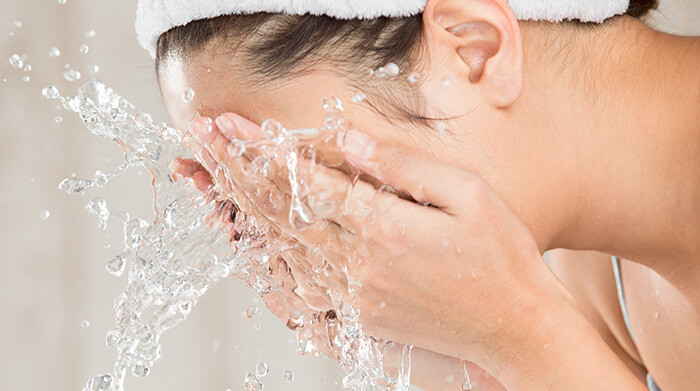 femme se rinçant le visage à l'eau claire