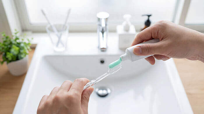 dentifrice sur une brosse à dents au dessus d'un lavabo de salle de bain