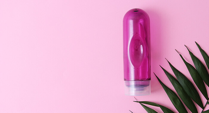 flacon de lubrifiant intime violet présenté sur un fond rose