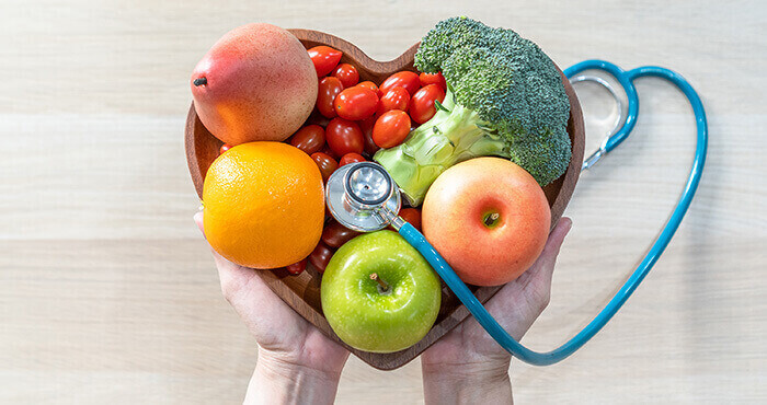 aliments favorables à la régulation du cholestérol dans un saladier en forme de coeur, avec un stéthoscope