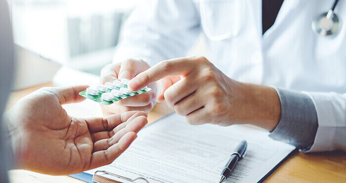 médecin tendant une plaquette de médicaments à un patient