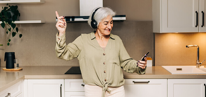 dame agée en train d'écouter de la musique dans sa cuisine