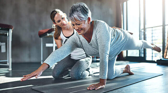 femme réalisant un exercie de renforcement musculaire en poids de corps, guidée par une coach