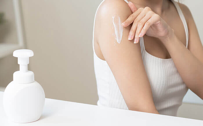 femme hydratant sa peau atopique à l'aide d'un baume hydratant