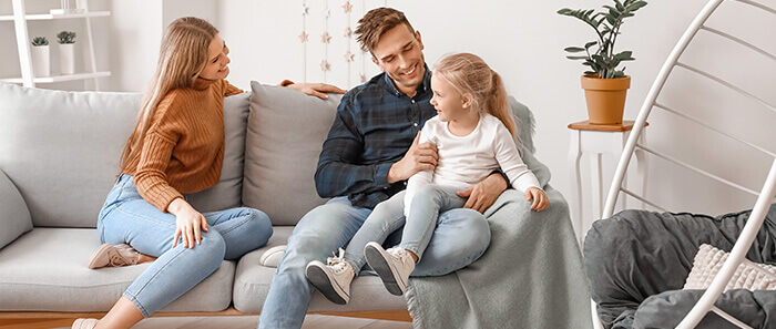 Parents et leur petite fille discutant sur un canapé