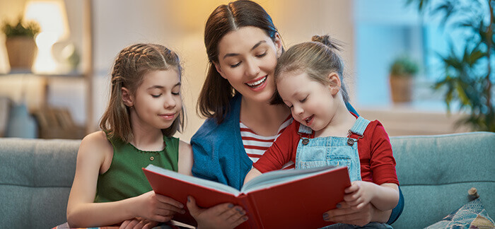 une maman listant un livre à ses deux petites filles