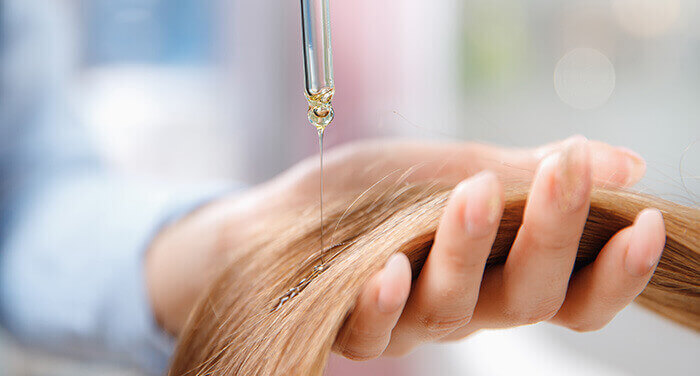 application d'une huiel végétale sur les cheveux à l'aide d'une pipette