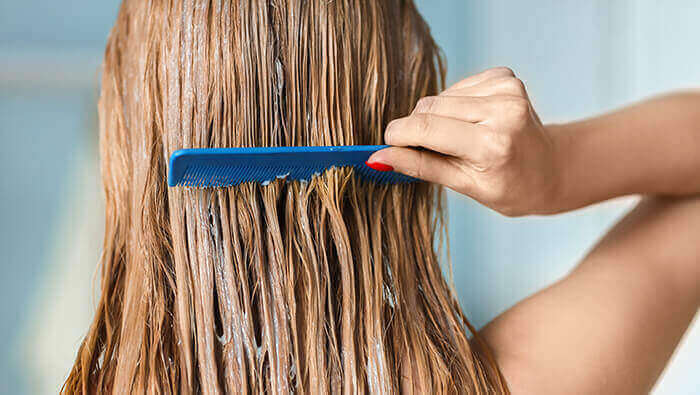 femme peignant ses cheveux sur lesquels un masque est appliqué