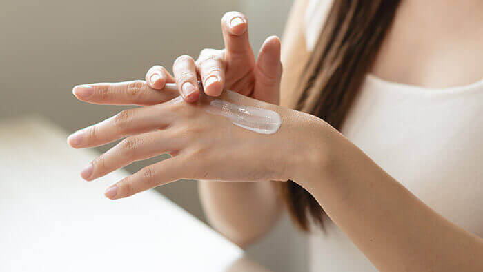 femme appliquant une crème de soin sur la peau de sa main