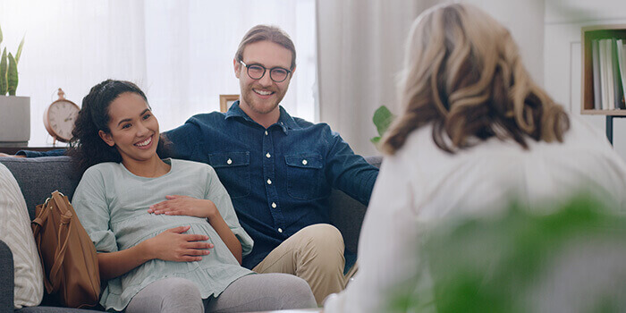 couple de futurs parents en entretien avec une sage-femme dans le cadre de la préparation à l'accouchement