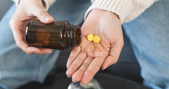 plan sur deux comprimés d'antibiotique de couleur jaune dans la paume de main d'une femme