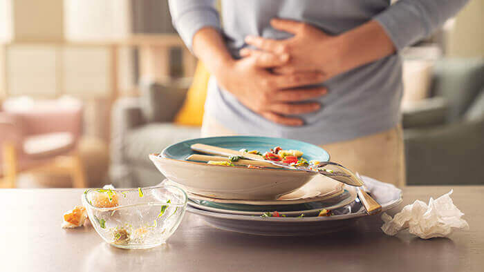 personne se tenant le ventre après avoir terminé un repas