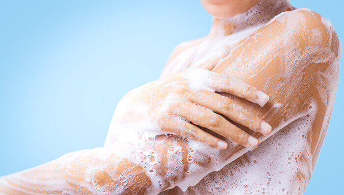 personne se lavant le bras à l'aide d'un soin moussant