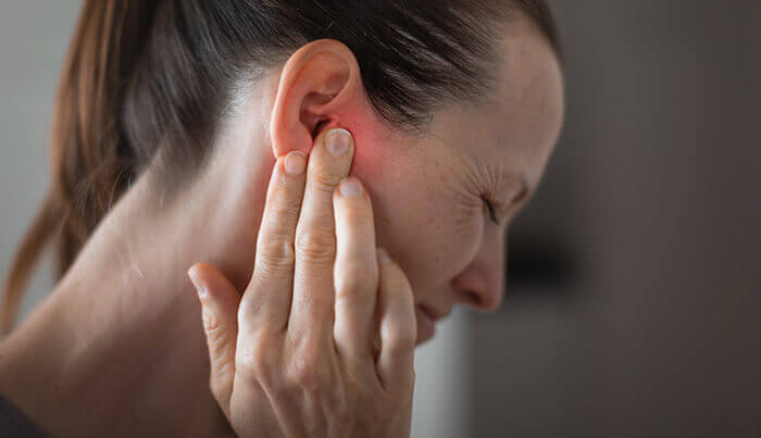 Femme se tenant l'oreille douloureuse