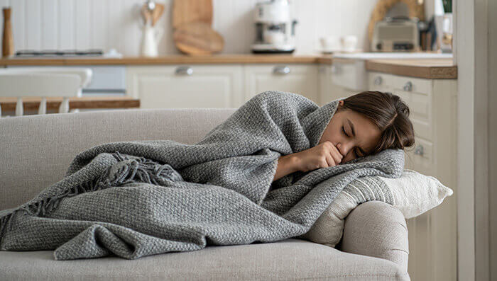 femme souffrant d'une bronchite se reposant sur son canapé