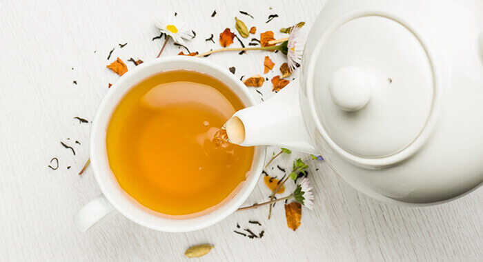tasse de tisane et théière blanche vues du dessus