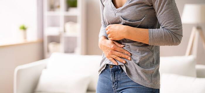 femme se tenant le ventre à cause de douleurs liées à de la constipation