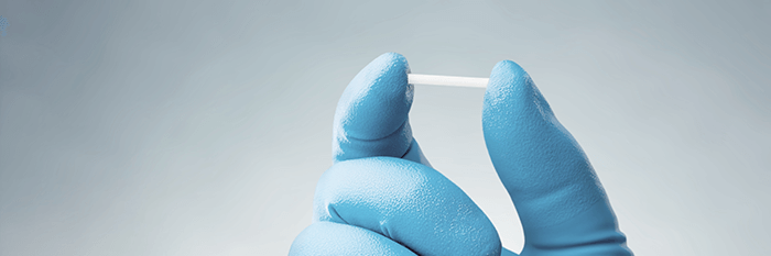 implant contraceptif tenu par une main gantée