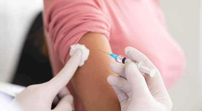 plan sur le bras d'une femme en train de se faire vacciner